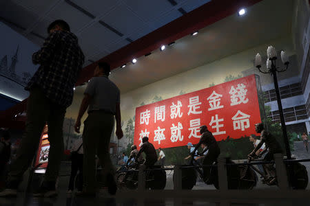 People visit an exhibition marking the 40th anniversary of China's reform and opening up at the Museum of Contemporary Art and Planning Exhibition Centre in Shenzhen, Guangdong province, China December 4, 2018. The sign reads "Time is money, efficiency is life" . REUTERS/Thomas Suen