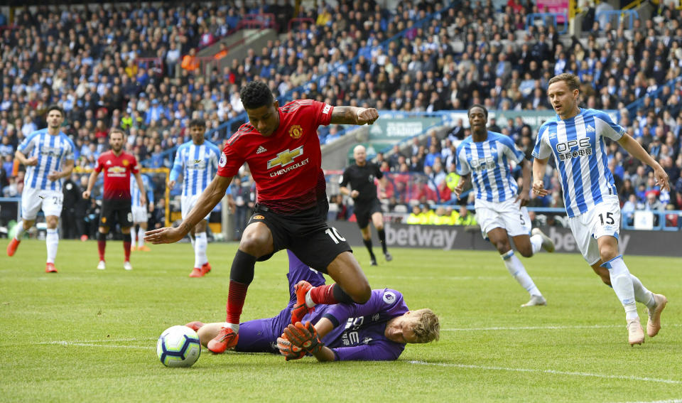 Manchester United's Marcus Rashford, top, and Huddersfield Town goalkeeper Jonas Lossl battle for the ball during the English Premier League soccer match at the John Smith's Stadium, Huddersfield, England, Sunday May 5, 2019. (Anthony Devlin/PA via AP)
