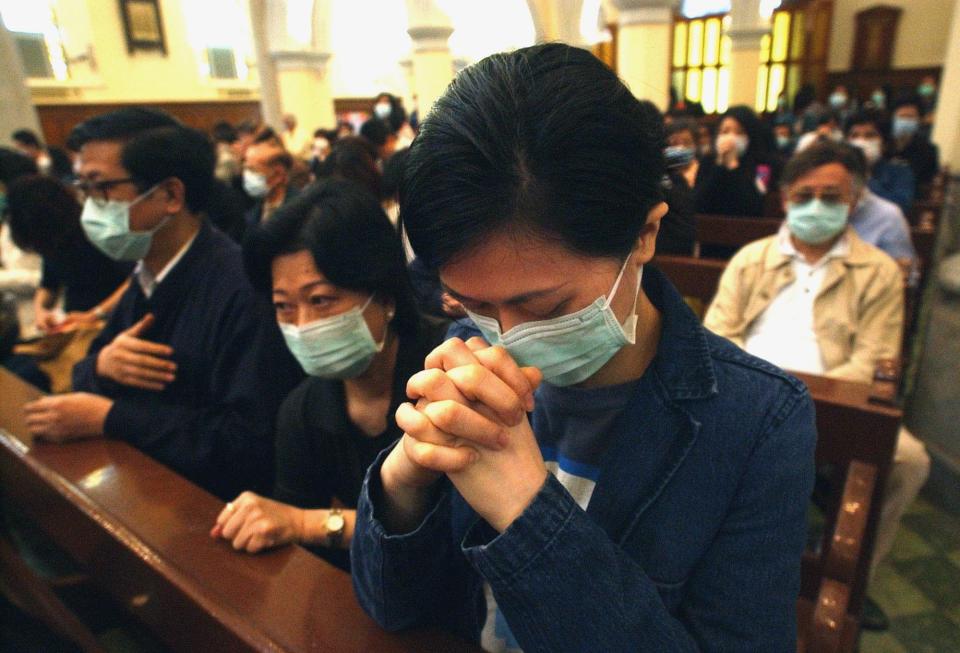 Roman Catholic worshippers wearing protective masks against severe acute respiratory syndrome, or SARS, pray during Good Friday Mass at Hong Kong's Catholic Cathedral of the Immaculate Conception, Friday, April 18, 2003.