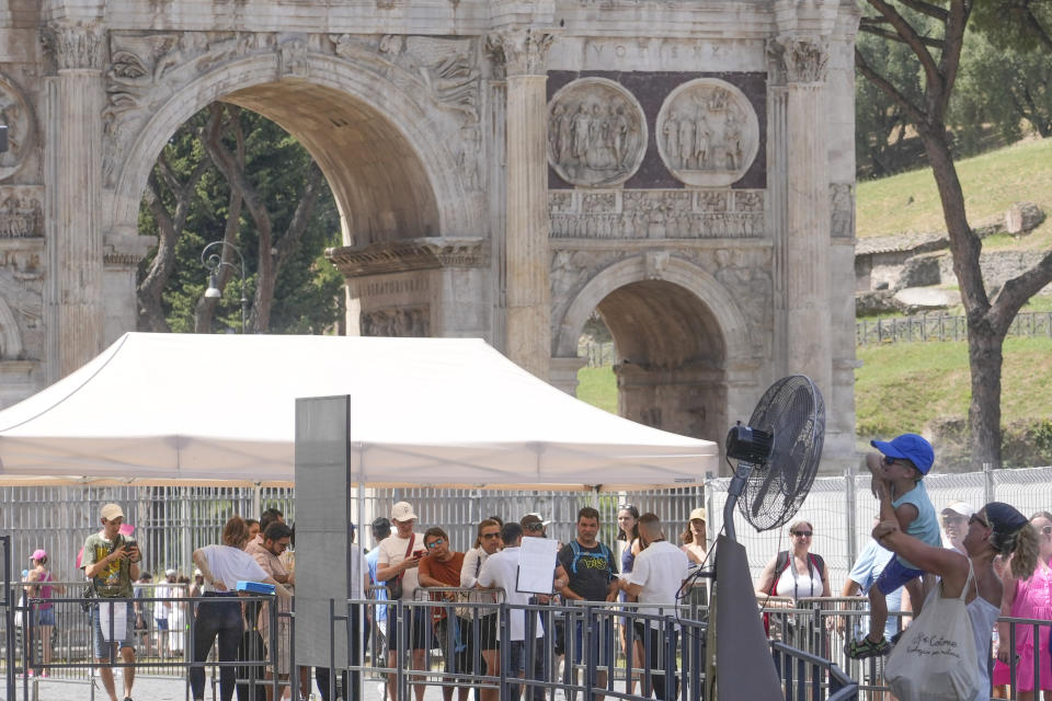 A woman and a child cool off near a fan as they queue to enter Rome's Colosseum, Tuesday, July 18, 2023. Tourist flock to the eternal city while scorching temperatures grip central Italy with Rome at the top of the red alert list as one of the hottest cities in the country. (AP Photo/Gregorio Borgia)