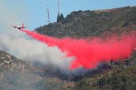 <p>A firefighting aircraft drops fire retardant on the flames in the Angeles National Forest near Los Angeles. (Reuters)</p>