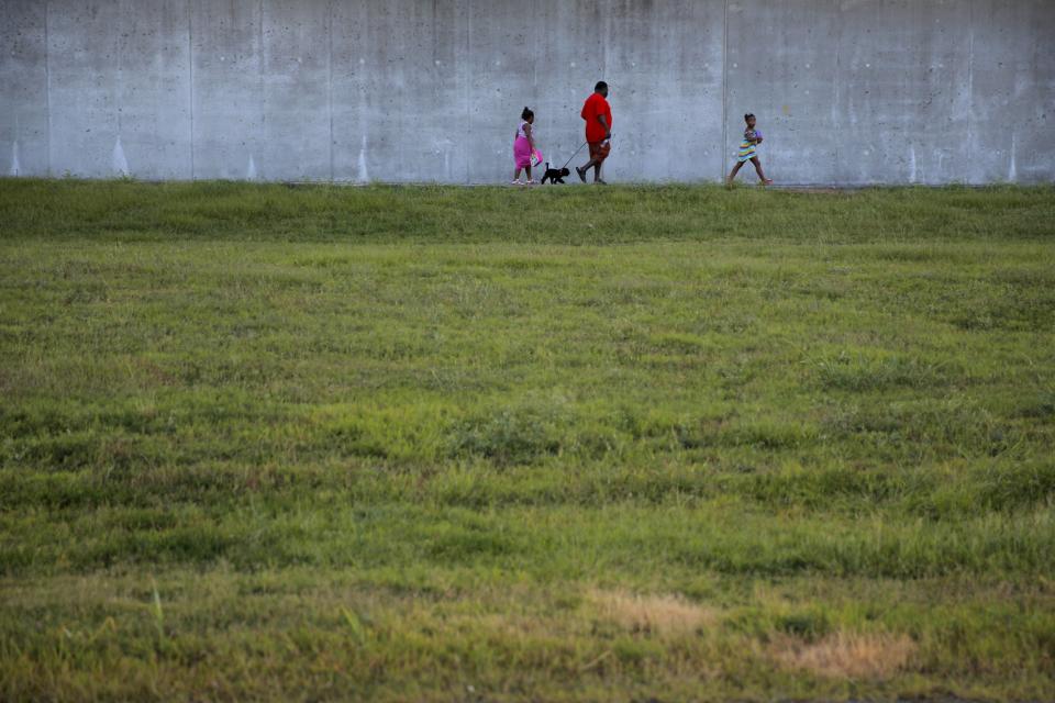 Lower Ninth Ward area residents walk by a levee wall reconstructed after Hurricane Katrina at the Lower Ninth Ward canal in New Orleans, Louisiana, August 16, 2015. (REUTERS/Carlos Barria)