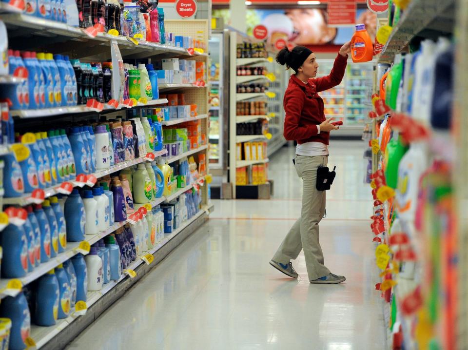 Target employee places laundry detergent on shelf in aisle of Target store