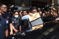 Malaysia's Prime Minister and Finance Minister Anwar Ibrahim, center, poses with a briefcase containing his 2023 budget speech as he leaves the Finance Ministry building for the Parliament in Putrajaya, Malaysia, Friday, Feb. 24, 2023. (AP Photo)