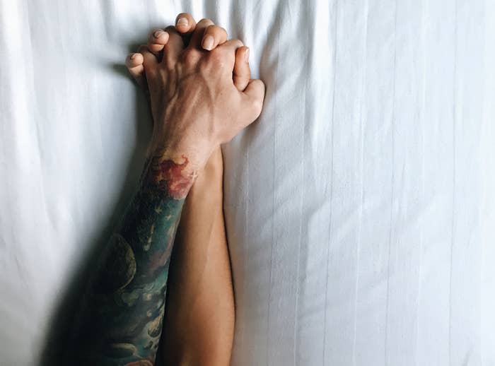 Two arms holding hands in bed