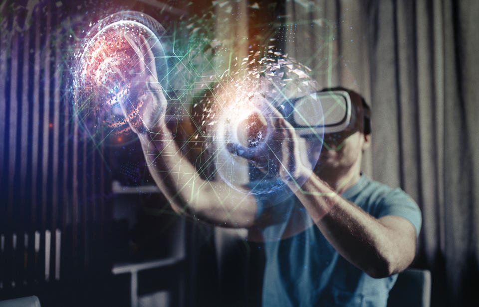 Image of a person wearing a VR headset and two 3D orbs in front of his hands.