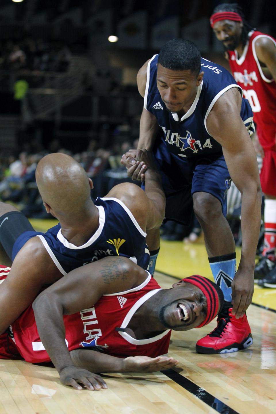 East's Nick Cannon, front left, reaches for West's Kevin Hart, bottom, as East's Bruce Bowen, top left, gets up in the first half as they participate in the NBA All-Star Celebrity basketball game in New Orleans, Friday, Feb. 14, 2014. East won 60-56. (AP Photo/Bill Haber)