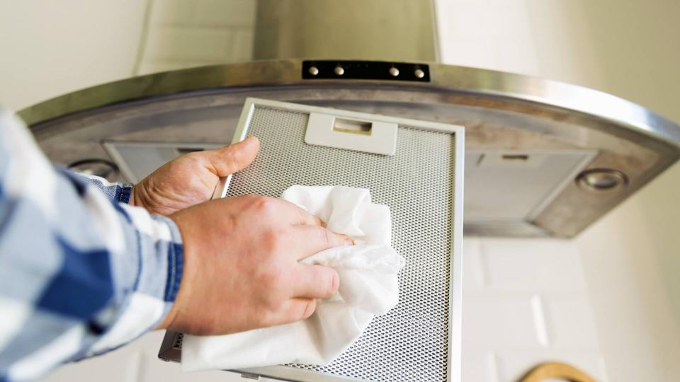 Man's hands cleaning aluminum mesh filter for cooker hood.