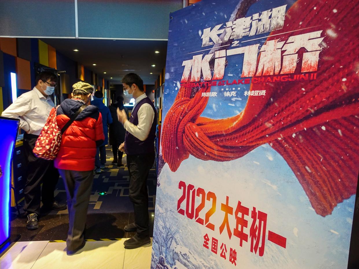 People in China entering a movie theatre behind a poster of the Chinese movie "Water Gate Bridge."