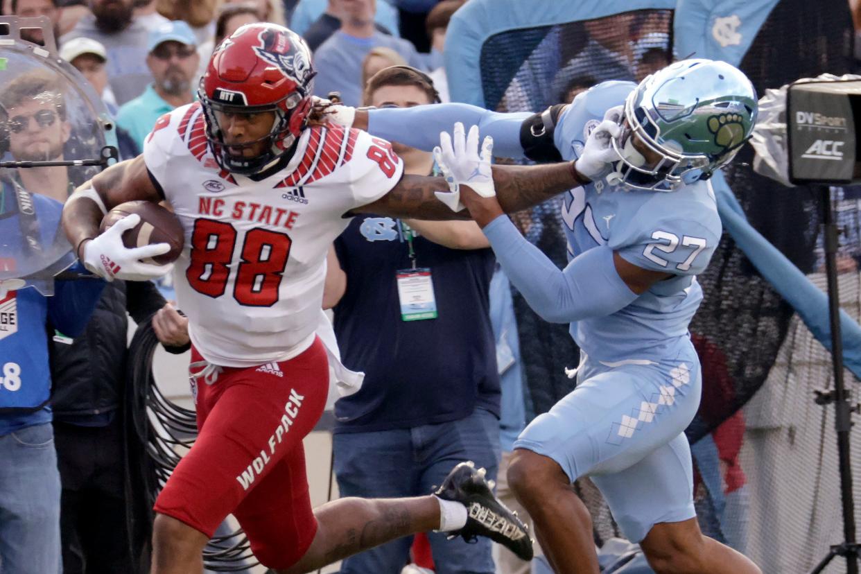 North Carolina State wide receiver Devin Carter (88) tries to stave off a tackle attempt by North Carolina defensive back Giovanni Biggers (27) as he runs for a big gain after a reception during the first half of an NCAA college football game Friday, Nov. 25, 2022, in Chapel Hill, N.C. (AP Photo/Chris Seward)
