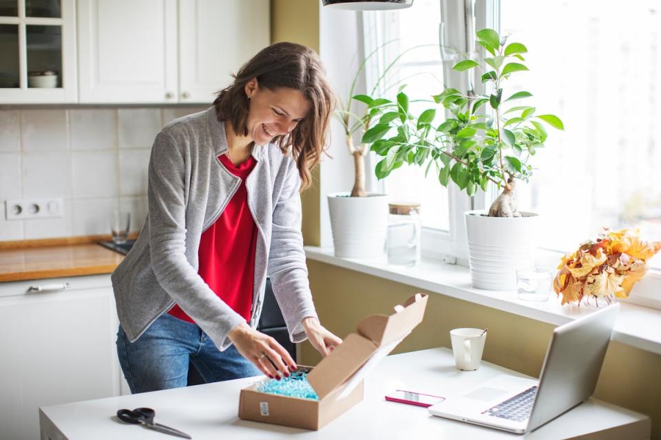 A person standing while opening a small box on a table. 