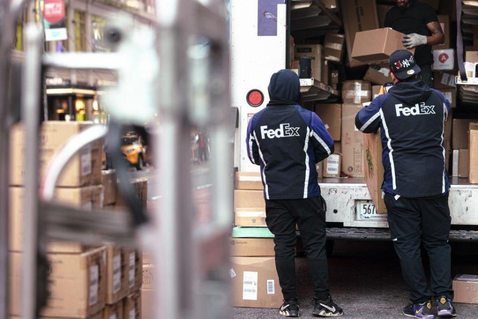 Dos trabajadores de FedEx descargando paquetes de un camión