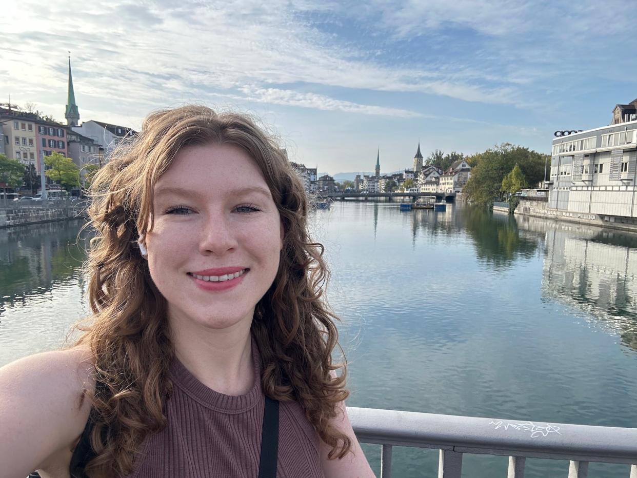 selfie of smiling woman standing on a bridge over a canal with old swiss buildings on the banks