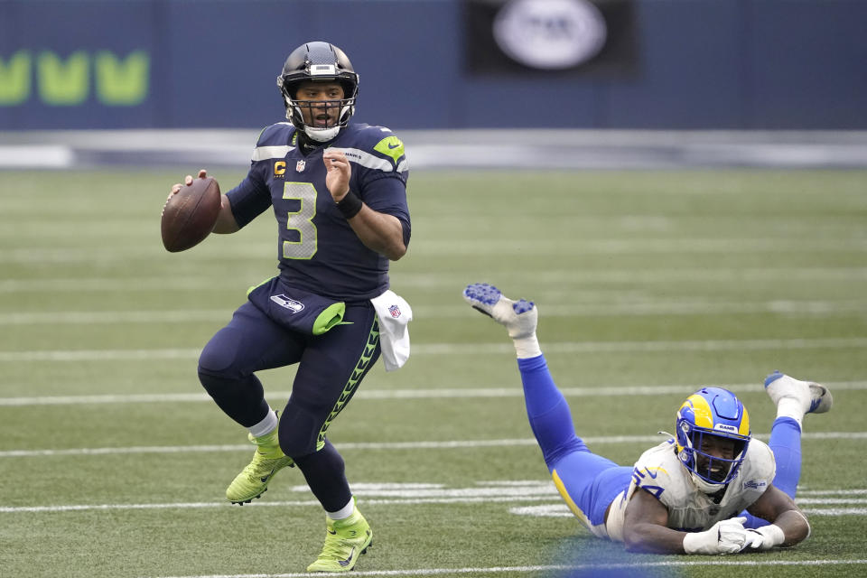 Seattle Seahawks quarterback Russell Wilson (3) scrambles away from Los Angeles Rams outside linebacker Leonard Floyd during the second half of an NFL wild-card playoff football game, Saturday, Jan. 9, 2021, in Seattle. (AP Photo/Ted S. Warren)