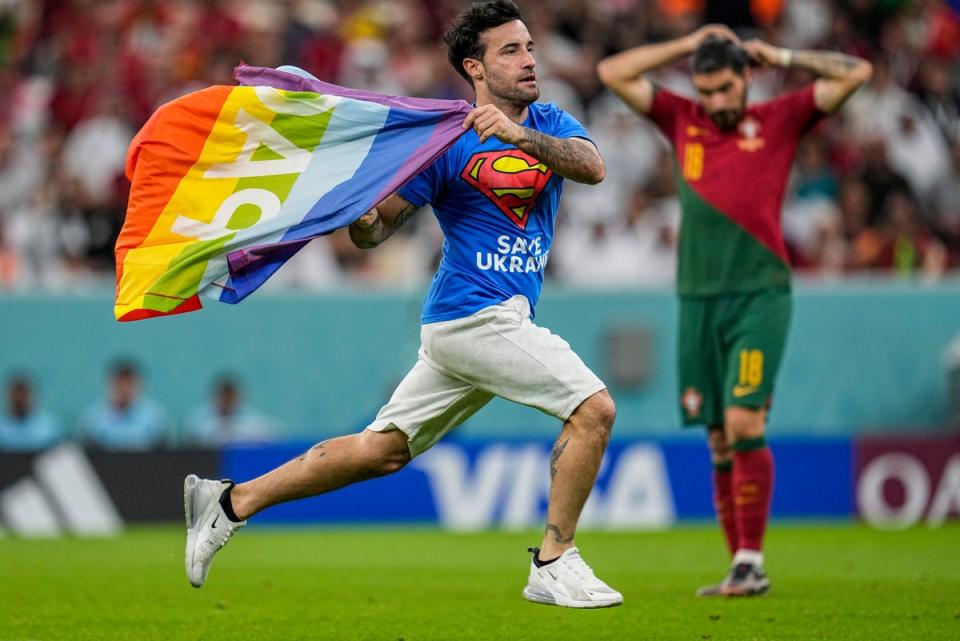 Um invasor de estádio atravessa o campo com uma bandeira do arco-íris durante a partida do Grupo H da Copa do Mundo entre Portugal e Uruguai, no Lusail Stadium, em Lusail (AP)