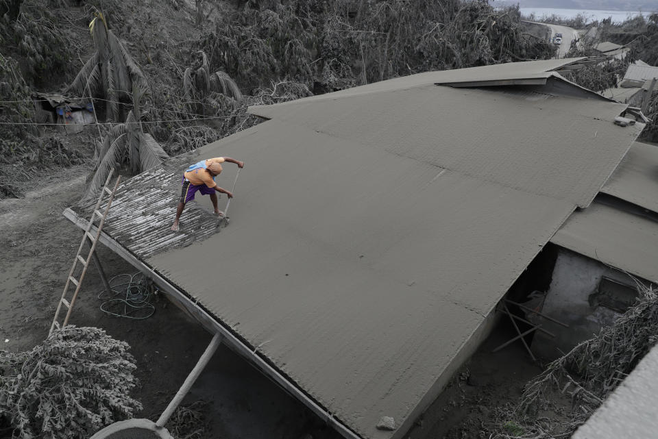 In this Tuesday, Jan. 14, 2020, photo, A resident clears volcanic ash from his roof in Laurel, Batangas province, southern Philippines on Tuesday, Jan. 14, 2020. Taal volcano is spewing ash half a mile high and trembling with earthquakes constantly as thousands of people flee villages darkened and blanketed by heavy ash. (AP Photo/Aaron Favila)