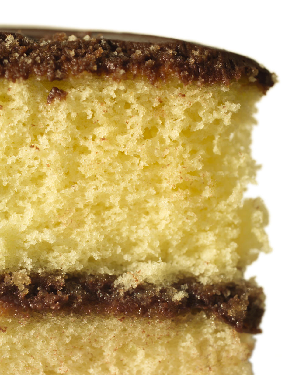 Close-up of a slice of layered sponge cake with a thin layer of chocolate frosting