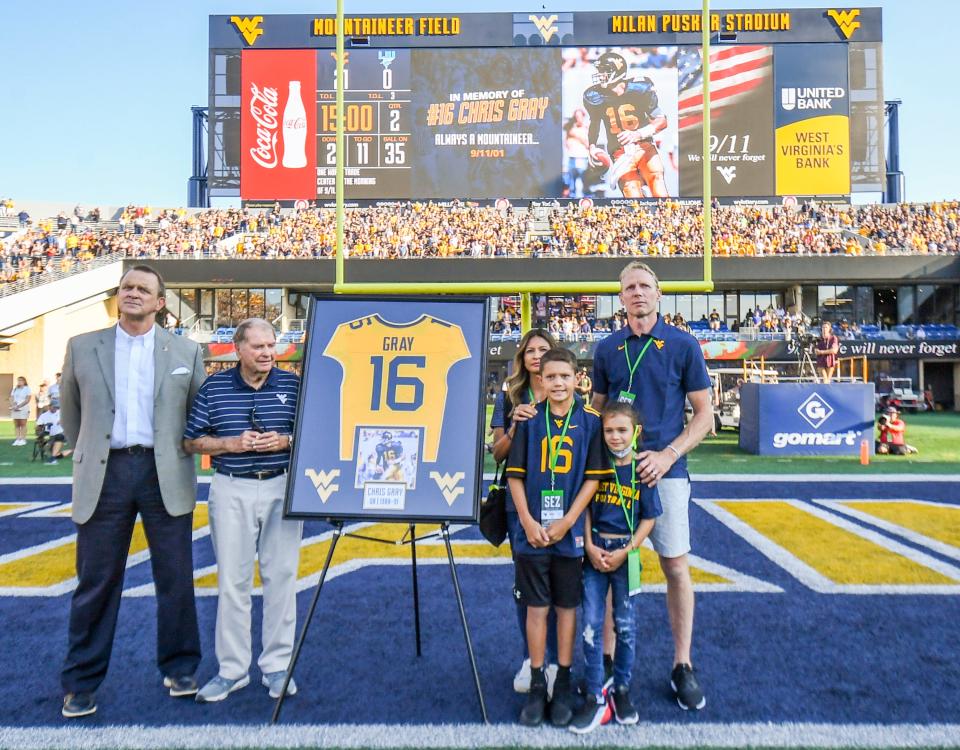 Chris Gray's brother Tim Gray (far right) and family are recognized alongside Chris's No. 16 West Virginia football jersey prior to a Mountaineers' game on Sept. 11, 2021. Second from left is Chris' coach at West Virginia, Don Nehlen.