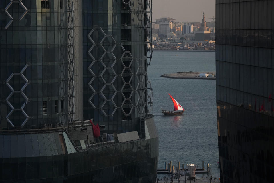 A boat with a Canadian flag sail moves through Doha Harbor, in Doha, Tuesday, Nov. 22, 2022. (AP Photo/Ashley Landis)