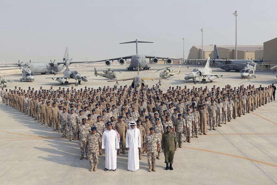 FILE - In this photo released by Qatar News Agency, QNA, the Qatari Emir Sheikh Tamim bin Hamad Al Thani, center front, poses for a photo with members of the Emiri Air Force at al-Udeid Air Base in Doha, Qatar, Sept. 11, 2017. Qatar will be on the world stage like it never has before as the small, energy-rich nations hosts the 2022 FIFA World Cup beginning this November. (QNA via AP, File)