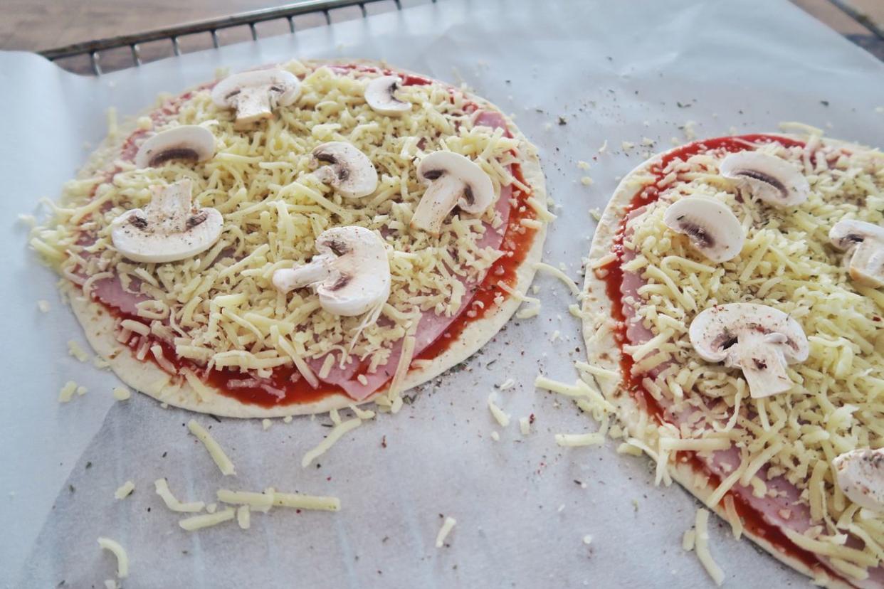 Homemade quick snack pizza on tortillas with ham cheese and mushrooms