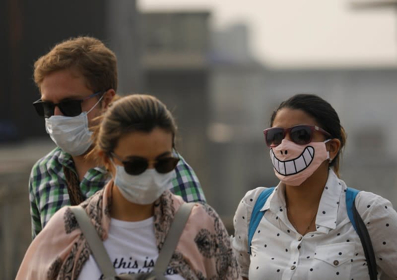 Tourists are seen with protective masks on a smoggy morning in the old quarters of Delhi