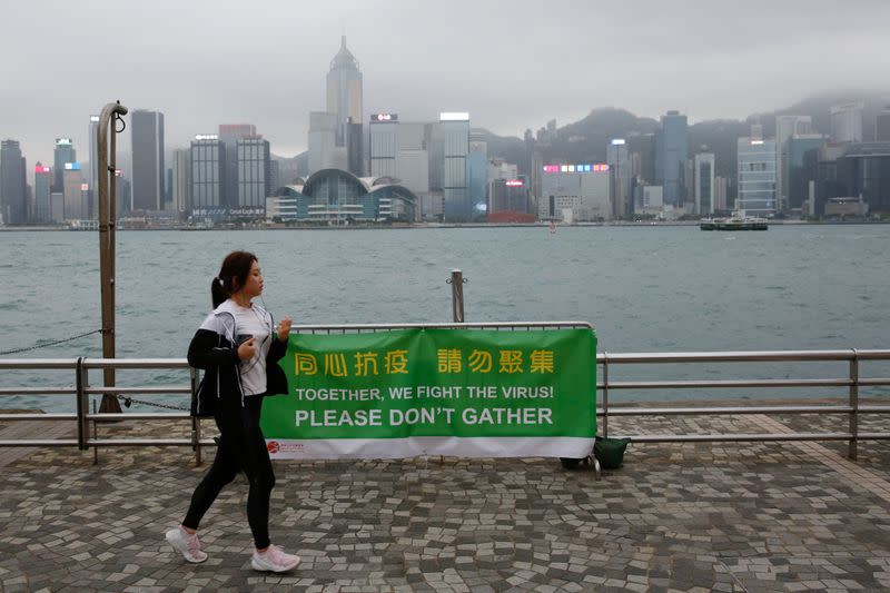 FILE PHOTO: A woman runs past a banner of health advice at Tsim Sha Tsui’s tourist attraction, following the novel coronavirus disease (COVID-19) outbreak, in Hong Kong