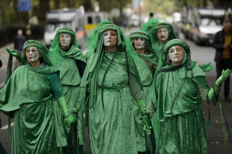 Green costumed Extinction Rebellion climate change demonstrators walk together in silent protest on Millbank in London, Tuesday, Oct. 8, 2019. Hundreds of climate change activists camped out in central London on Tuesday during a second day of world protests by the Extinction Rebellion movement to demand more urgent actions to counter global warming. (AP Photo/Matt Dunham)