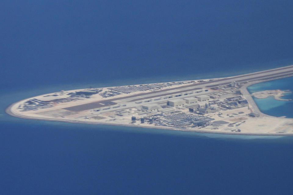 FILE - In this Friday, April 21, 2017, file photo, an airstrip, structures, and buildings on China's man-made Subi Reef in the Spratly chain of islands in the South China Sea are seen from a Philippine Air Force C-130 transport plane of the Philippine Air Force. A Chinese naval officer says China may further fortify man-made islands in the South China Sea depending on threats faced by the outposts. Navy academy researcher Senior Capt. Zhang Junshe last week repeated China's stance that it has the legal right to take whatever measures it deems appropriate on the islands in the South China Sea, which China claims virtually in its entirety. (AP Photo/Bullit Marquez, File)