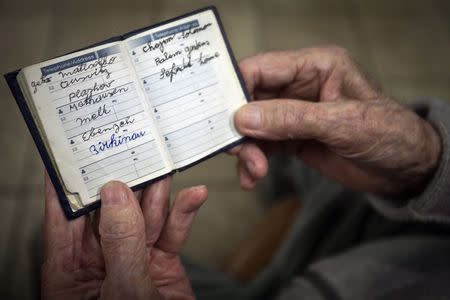 90 year old Holocaust survivor Hy Abrams poses for a portrait with a book that he carries with him everyday that documents all the different concentration camps he was held in during the second World War, in the Brooklyn borough of New York January 15, 2015. REUTERS/Carlo Allegri