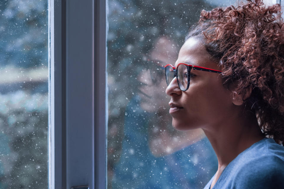 Lonely black woman near window thinking about something and winter snow