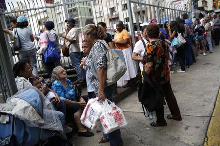 People stand in line to buy food outside a supermarket in Caracas November 14, 2014. Picture taken November 14. REUTERS/Carlos Garcia Rawlins