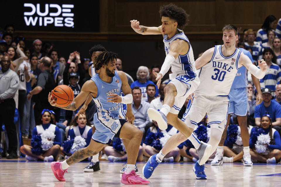 North Carolina's RJ Davis (4) passes as Duke's Tyrese Proctor (5) Kyle Filipowski (30) defend during the second half of an NCAA college basketball game in Durham, N.C., Saturday, March. 9, 2024. (AP Photo/Ben McKeown)