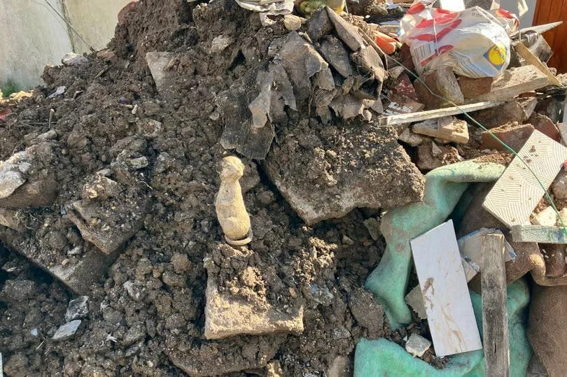 A broken meerkat garden ornament among a pile of rubble taken from Keyham gardens