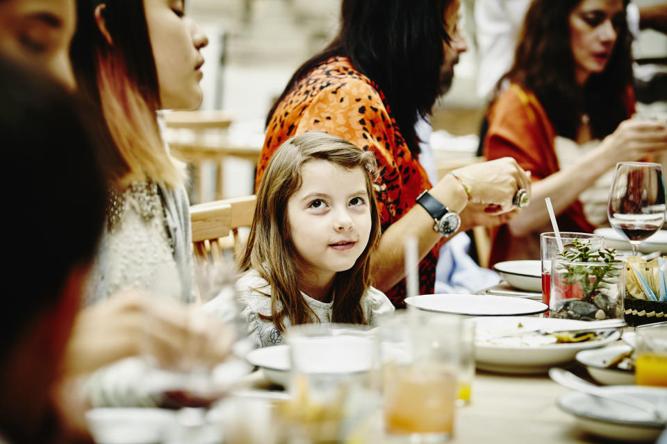 Smiling young girl sitting with family during party in restaurant