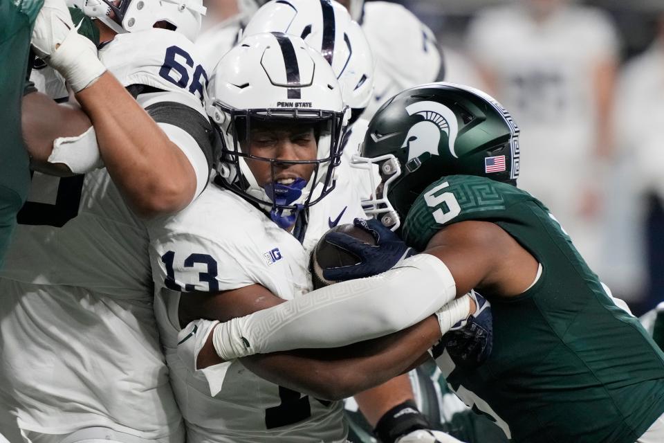 Penn State running back Kaytron Allen (13) is tackled by Michigan State linebacker Jordan Hall (5) during the first half at Ford Field in Detroit on Friday, Nov. 24, 2023.