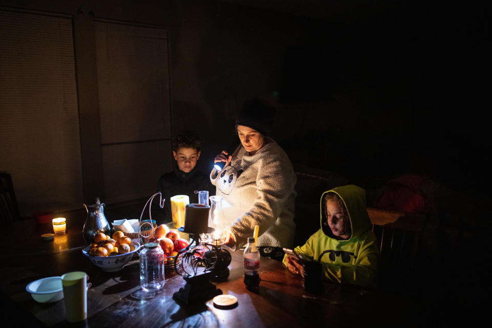Manessa Grady ajusta una lámpara de aceite mientras pasa tiempo con sus hijos Zechariah, de 8 años, a la izquierda, y Noah, de 9 años, en su casa en Austin, Texas, el martes, 16 de febrero de 2021, que ha estado sin electricidad desde la mañana del lunes. (Tamir Kalifa/The New York Times).