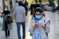 Shoppers, wearing protective masks due to the Covid-19 pandemic, walk past shops in Vali-asr Square in the Iranian capital Tehran