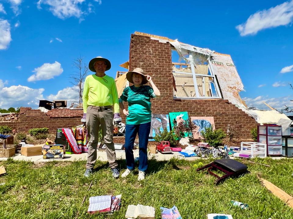 John and Valerie Bernhart stand with what remains of their Blackburn Lane home following Wednesday's destructive storms. Though the home is a total loss, they are one of many families receiving continued support from churches, volunteers and neighbors.