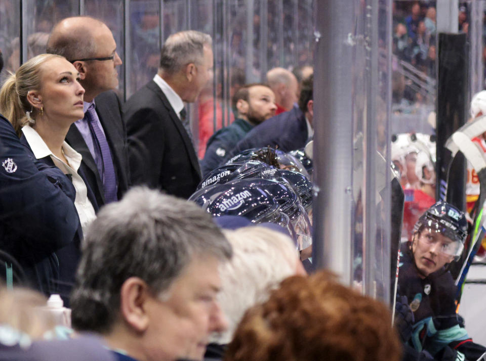 FILE - Jessica Campbell, left, assistant coach for the Coachella Valley Firebirds, works alongside Seattle Kraken coaches behind the bench during the second period of an NHL preseason hockey game against the Calgary Flames, Sept. 25, 2023, in Seattle. Jessica Campbell will become the first woman to work on the bench of an NHL franchise after the Seattle Kraken hired her as an assistant coach Wednesday, July 3, 2024. (AP Photo/Jason Redmond, File)