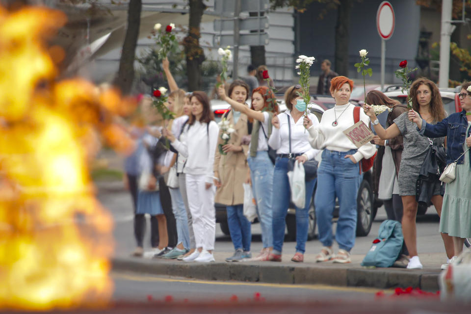 Belarusian opposition supporters hold flowers and flash victory signs during a protest in Minsk, Belarus, Thursday, Aug. 20, 2020. Demonstrators are taking to the streets of the Belarusian capital and other cities, keeping up their push for the resignation of the nation's authoritarian leader. President Alexander Lukashenko has extended his 26-year rule in a vote the opposition saw as rigged. (AP Photo/Dmitri Lovetsky)