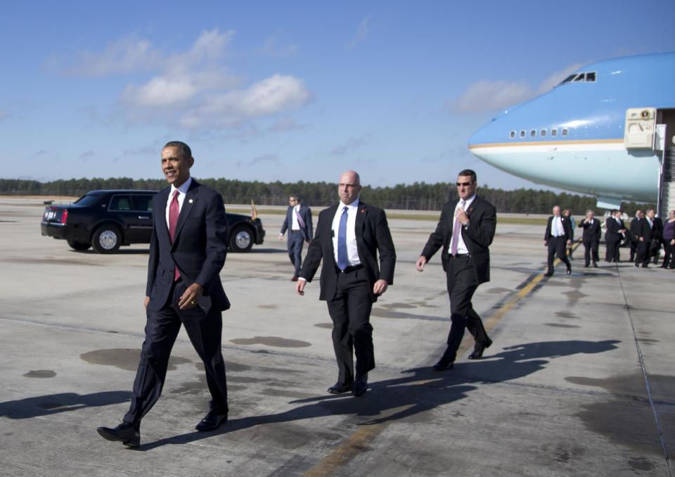 President Barack Obama walks across the tarmac to greet people as he arrives on Air Force One at Raleigh-Durham International Airport in Morrisville, N.C., Wednesday, Jan. 15, 2014, en route to North Carolina State University where he will speak about the economy. (AP Photo/Carolyn Kaster)