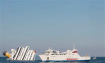 The luxury cruise ship Costa Concordia, left, leans on its side after running aground off the tiny Tuscan island of Giglio, Italy, Saturday, Jan. 14, 2012. The luxury cruise ship ran aground off the coast of Tuscany, sending water pouring in through a 160-foot (50-meter) gash in the hull and forcing the evacuation of some 4,200 people from the listing vessel early Saturday, the Italian coast guard said. (AP Photo/Gregorio Borgia)