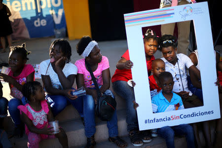 Haitian immigrant children hold a banner that reads "Childhood without conditions", at a church in Santiago, Chile, December 18, 2016. Picture taken December 18, 2016. REUTERS/Ivan Alvarado