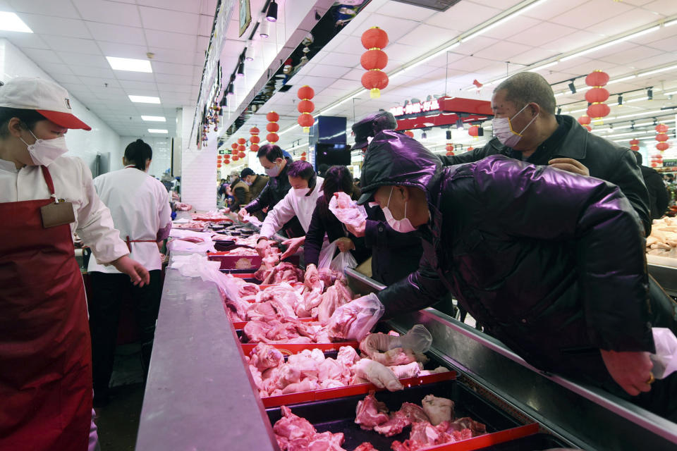 People wearing masks buy meats at a supermarket in Hangzhou in east China's Zhejiang province, Saturday, Feb. 08, 2020. China's communist leaders are striving to keep food flowing to crowded cities despite anti-disease controls, to quell fears of possible shortages and stave off price spikes from panic buying after most access to Wuhan was cut off Jan. 23. Food stocks in supermarkets ran low shortly after Beijing imposed travel curbs and extended the Lunar New Year holiday to keep factories, offices and other businesses closed and the public at home, attempting to prevent the virus from spreading. (Chinatopix via AP)