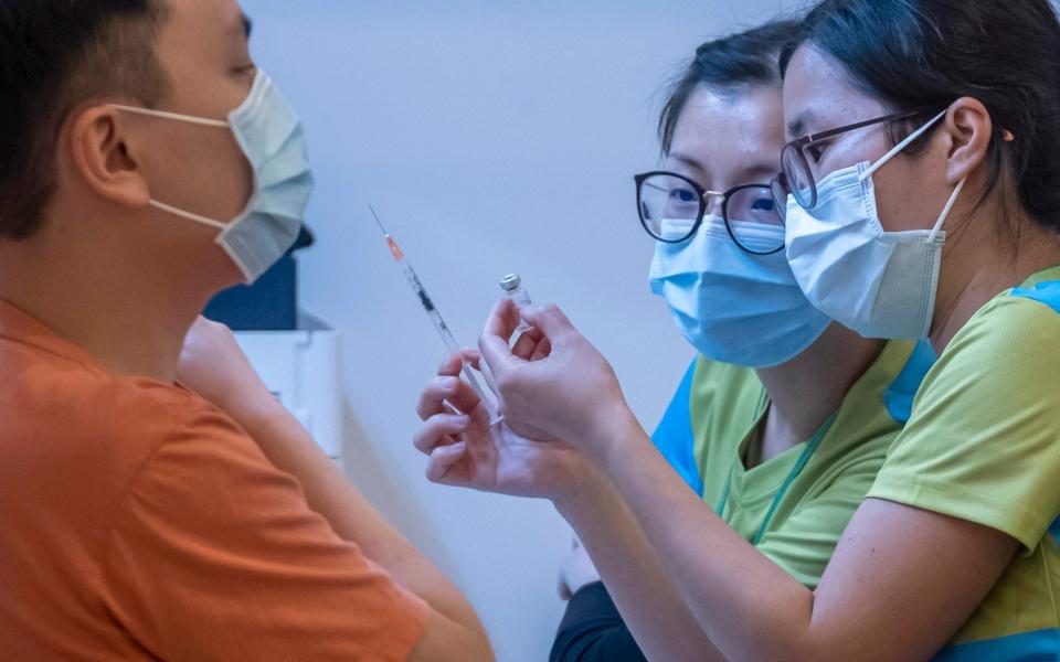 Health workers look at a vial and a syringe while administering a dose of the Sinovac Biotech COVID-19 vaccine at a community vaccination center in Hong Kong - Paul Yeung 