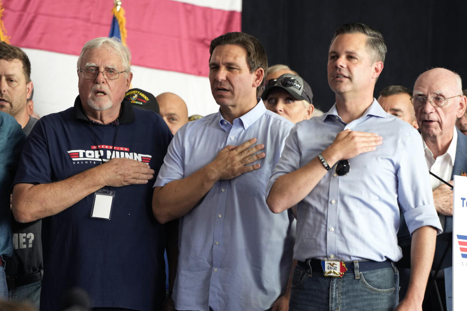 Republican presidential candidate Florida Gov. Ron DeSantis, center, stands with U.S. Rep. Zach Nunn, R-Iowa, right, during the Pledge of Allegiance at the start of Nunn's Annual BBQ, Saturday, July 15, 2023, in Ankeny, Iowa. (AP Photo/Charlie Neibergall)
