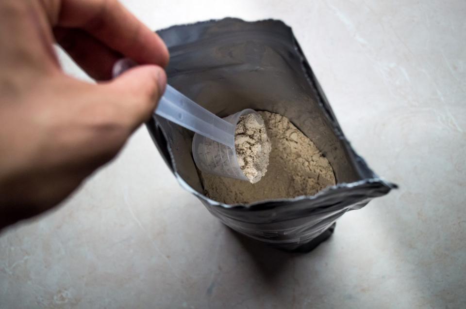 Hand Measuring Whey in a Bag of Whey Protein Powder