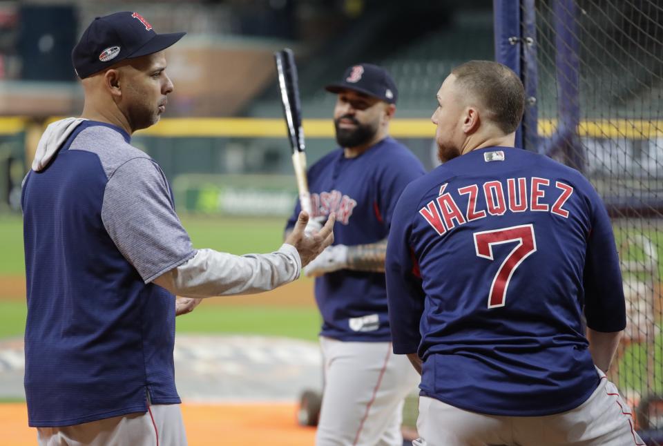 Boston Red Sox's Christian Vazquez, right, talks to manager Alex Cora, left, as Sandy Leon, center, looks on during a workout at Minute Maid Park, Monday, Oct. 15, 2018, in Houston. The Red Sox are to face the Houston Astros in Game 3 of the baseball American League Championship Series, Tuesday, Oct. 16. (AP Photo/Frank Franklin II)