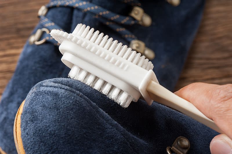 cleaning suede shoes using a suede brush to remove excess dirt